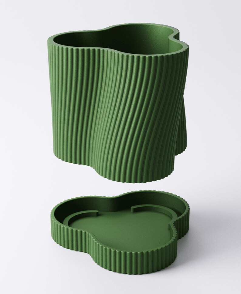 May include: A green, clover-shaped container and lid set. The container has a textured, vertical, ridged design that twists. The lid is a matching green with a clover shape and a recessed interior.