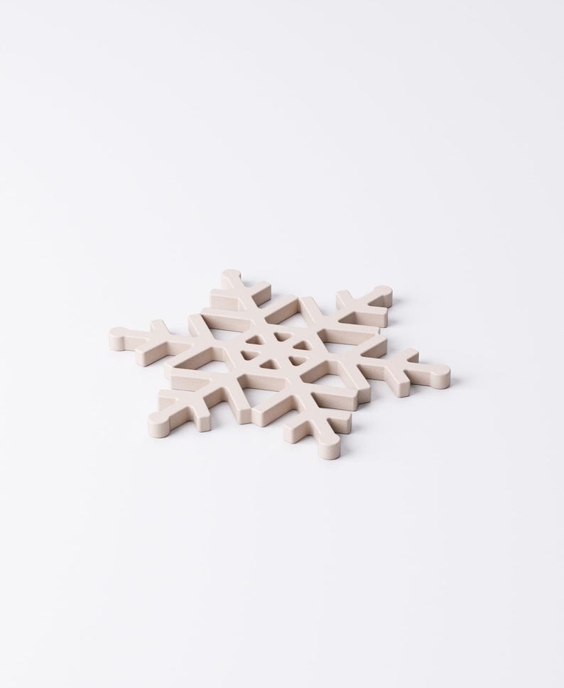 May include: A light beige snowflake-shaped decorative item. The snowflake has six symmetrical arms with intricate cut-out details. The item is made of a solid material and is set against a white background. Ideal for winter holiday decor.