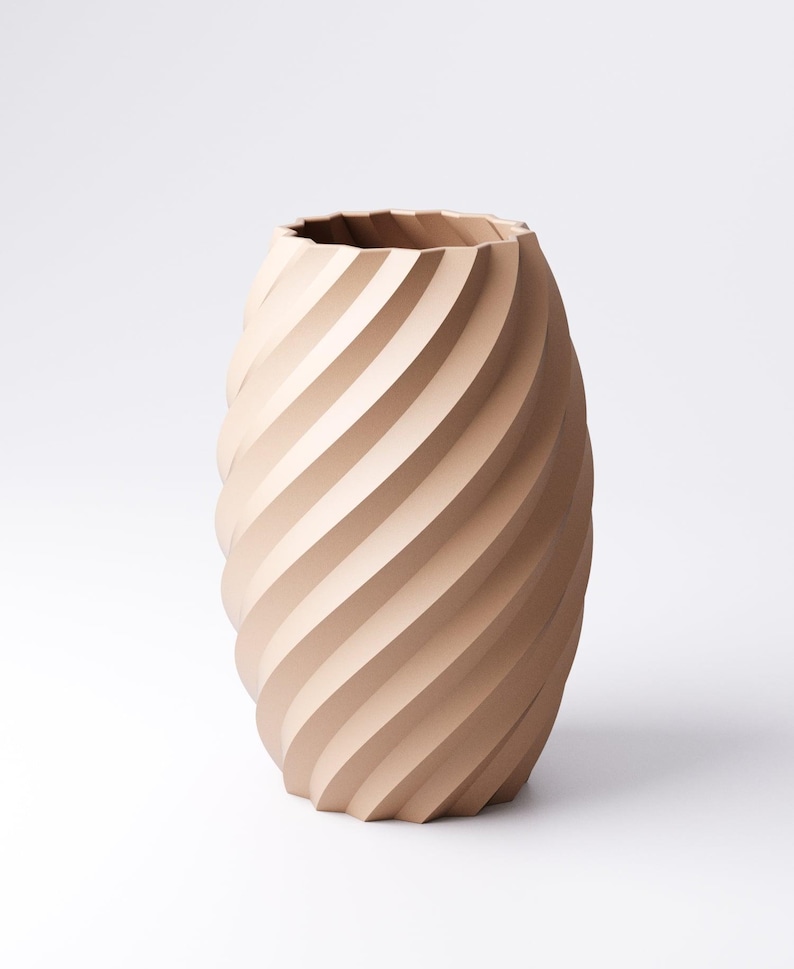 May include: A beige, decorative vase with a spiral design. The vase has a wide, oval shape and a textured surface created by the diagonal grooves. The top edge of the vase has a wavy, irregular pattern.