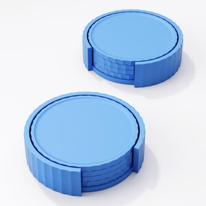 May include: Two stacks of blue coasters. Each coaster has a round, flat top and a ridged, cylindrical edge. The coasters are a light blue color and appear to be made of a solid material.