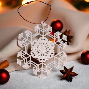 May include: A white snowflake ornament with intricate details hangs from a red string. The ornament is surrounded by red Christmas ornaments, star anise, and a cinnamon stick. The background features soft, blurred lights.