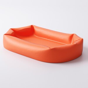 May include: An orange rectangular tray with rounded corners. The tray has a slightly raised edge and a smooth, matte finish. The product is designed to hold small items.