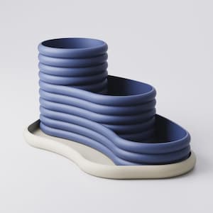 May include: A modern, abstract sculpture in shades of blue and off-white. The blue portion features a stacked, wavy design, while the base is a contrasting off-white, creating a unique, artistic piece. The sculpture is likely ceramic or a similar material.