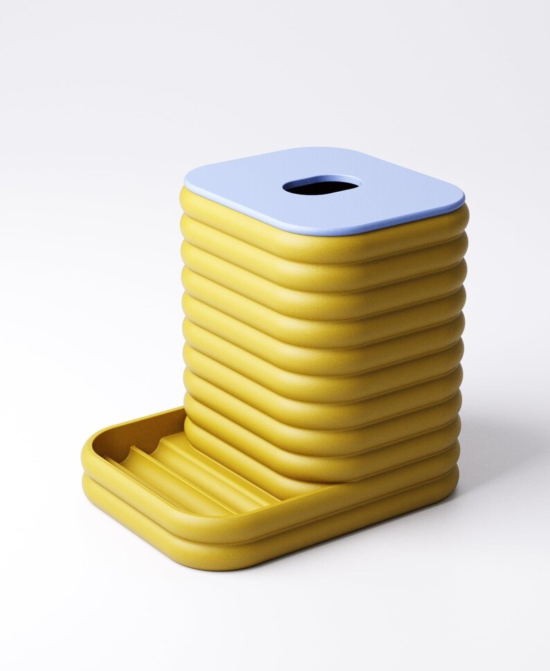 May include: A yellow and blue tissue box with a unique, ribbed design. The tissue box has a rectangular shape with a light blue top and a small opening. A small tray is attached to the side.