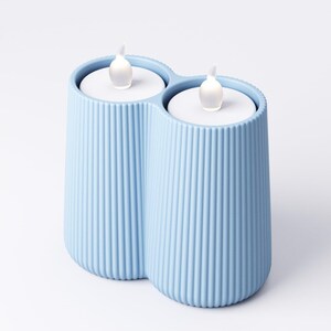 May include: A light blue, ribbed, double candle holder with two battery-operated LED candles. The candles have a realistic flickering flame effect. The holder is made of a solid material and has a modern design.