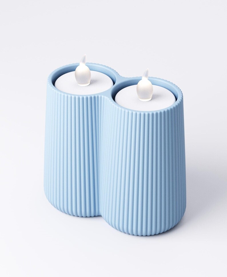 May include: A light blue, ribbed, double candle holder with two battery-operated LED candles. The candles have a realistic flickering flame effect. The holder is made of a solid material and has a modern design.