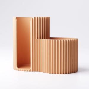 May include: A peach-colored, modern desk organizer with a unique, curved design. The organizer features a tall, rectangular section and a shorter, rounded section, both with vertical ridged detailing. The open design allows for easy access to stored items.