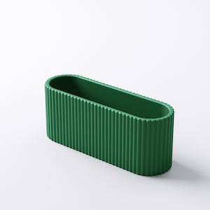 May include: A green, oval-shaped planter with vertical ribbed detailing. The planter has a smooth interior and a textured exterior. The design is modern and minimalist, suitable for various plants and decor styles.