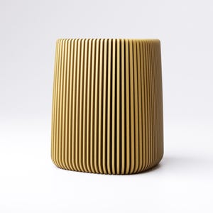 May include: A cylindrical, light brown container with vertical, evenly spaced grooves. The design gives the container a textured appearance. The object is set against a plain white background.
