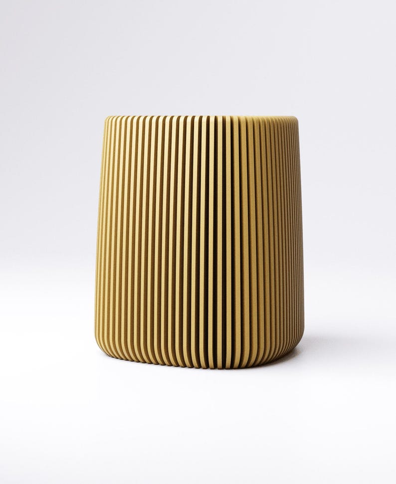 May include: A cylindrical, light brown container with vertical, evenly spaced grooves. The design gives the container a textured appearance. The object is set against a plain white background.