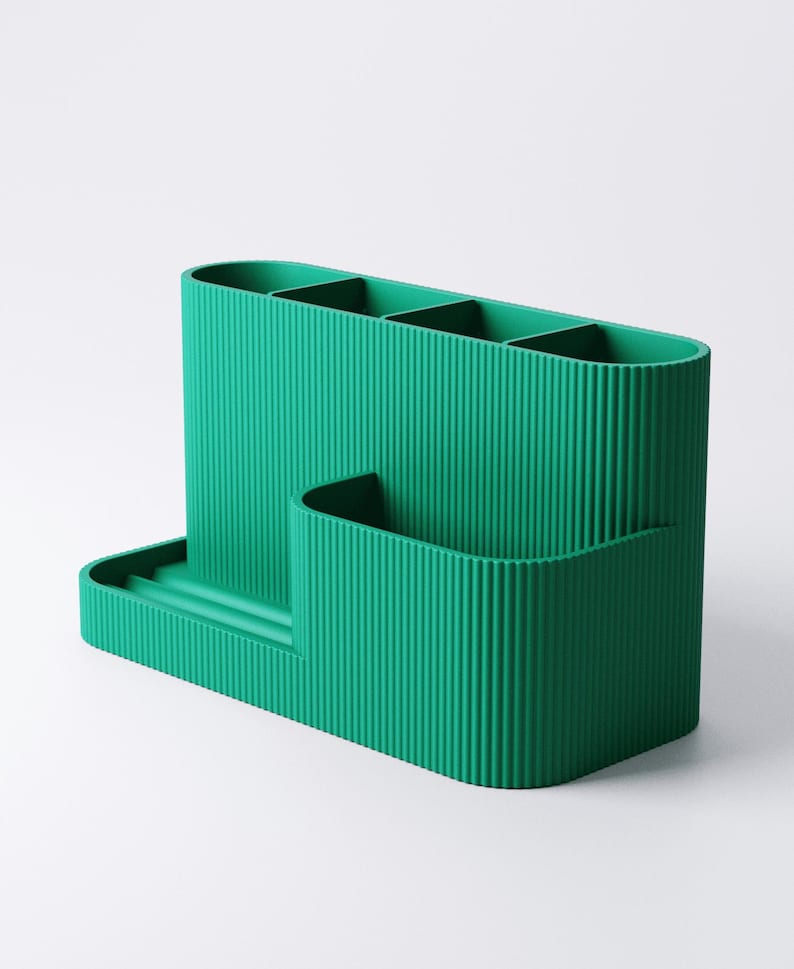 Pode incluir: Um organizador de secret&aacute;ria verde-azulado com textura canelada. Possui quatro compartimentos verticais, um pequeno bolso lateral e uma bandeja. O organizador &eacute; feito de um material s&oacute;lido e foi projetado para guardar canetas, l&aacute;pis e outros materiais de escrit&oacute;rio.