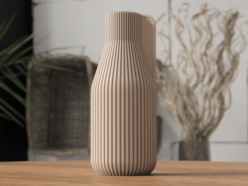 May include: A beige wooden vase with vertical brown stripes. The vase has a rounded base and a handle on the side. The vase is sitting on a wooden surface.