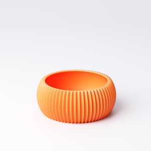 May include: An orange, round bowl with vertical ridged detailing. The bowl has a smooth interior and a textured exterior. The color is a vibrant, solid orange. The bowl is likely made of plastic or ceramic.