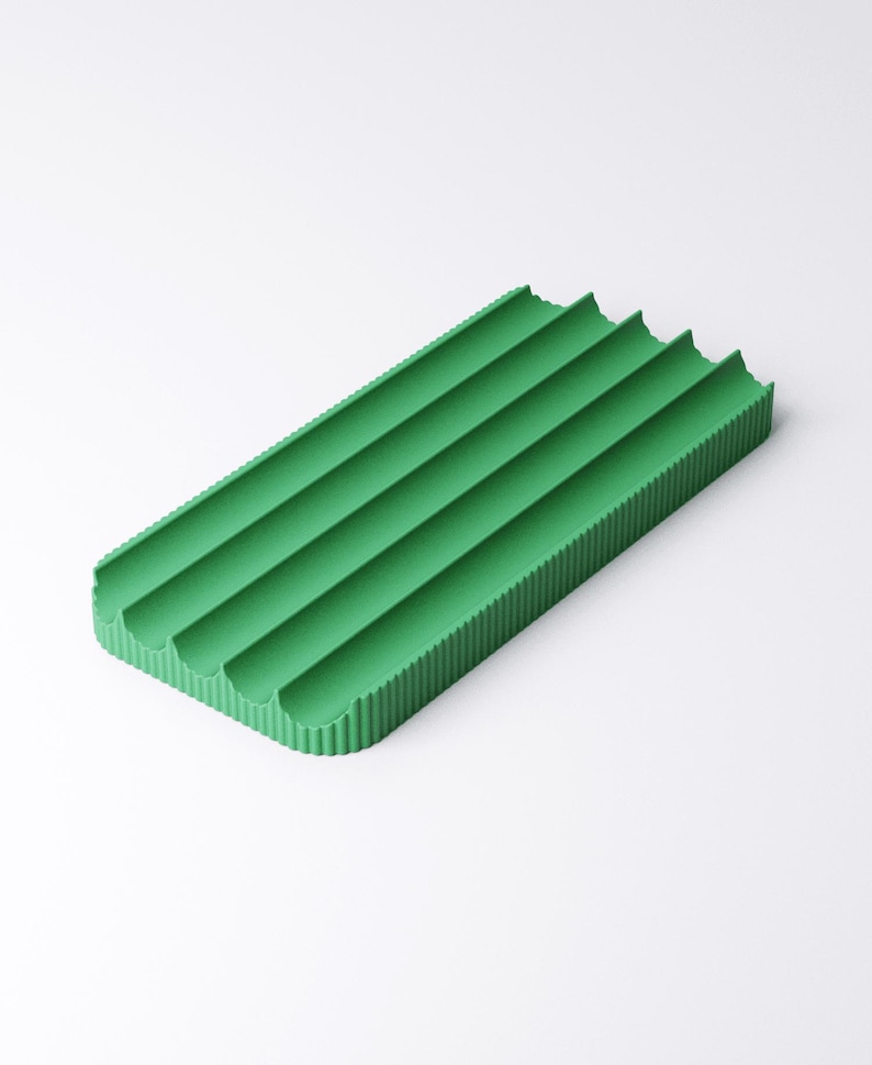 May include: A rectangular, green soap dish with four curved grooves. The dish has a textured, corrugated surface and is designed to hold soap bars. The bright green color adds a pop of color to any bathroom or kitchen.