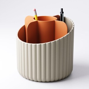 May include: A beige and orange desk organizer with a fluted exterior. The interior features a central orange compartment and several sections for pens and pencils. A yellow pencil and a black pen are visible.
