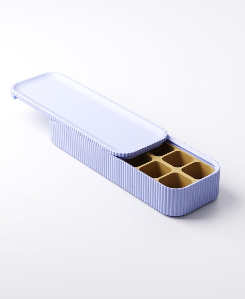 May include: A light purple ice cube tray with a matching lid. The tray has a ribbed exterior and contains six square compartments. The interior of the tray is a golden color.