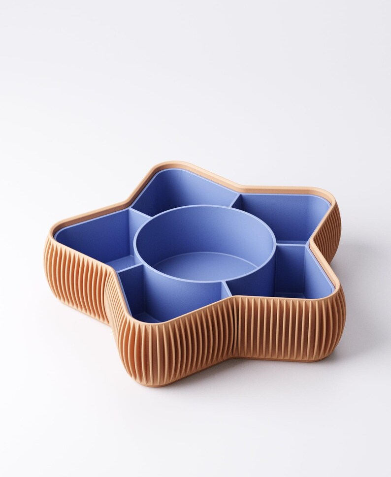 May include: A star-shaped organizer with a light brown, ribbed exterior and a blue interior. The organizer has a central circular compartment and several surrounding sections, ideal for storing small items. The design is modern and functional.