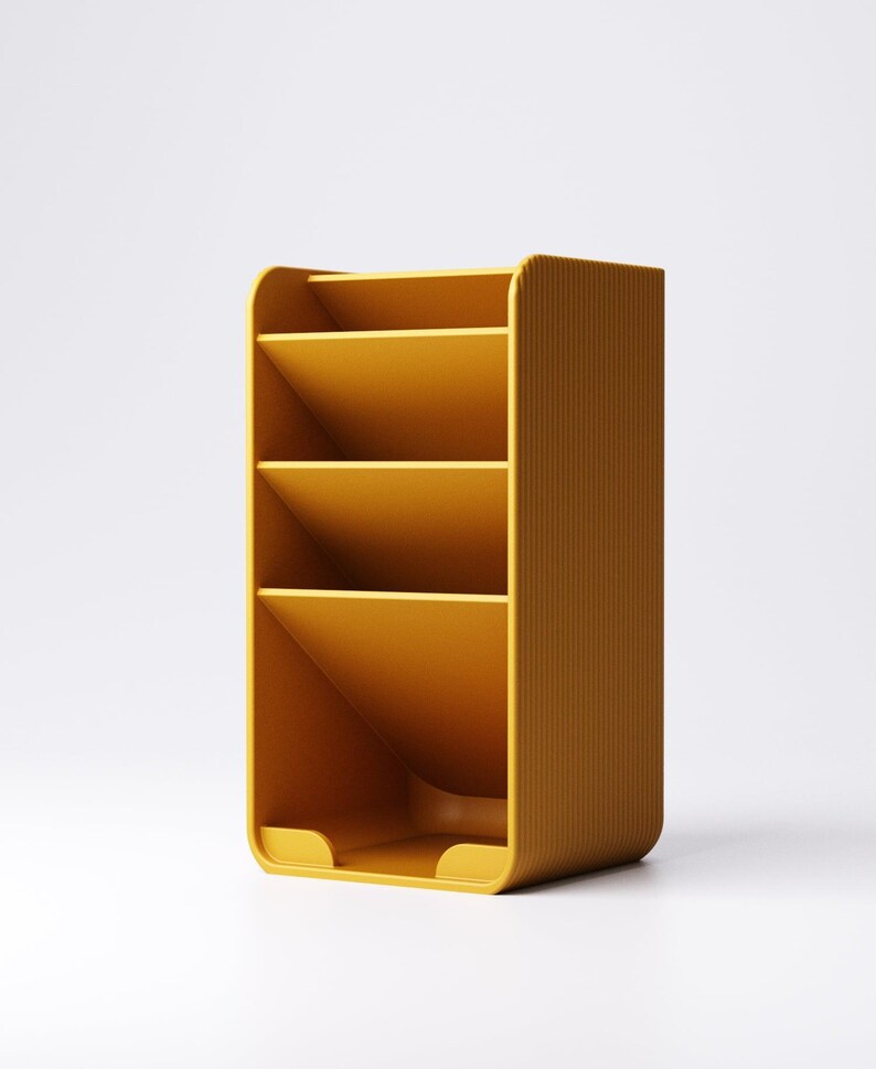 May include: Mustard yellow desk organizer with four angled compartments. The organizer has a rounded top and bottom with vertical ribbed detailing on the sides. The compartments are designed to hold papers or office supplies.