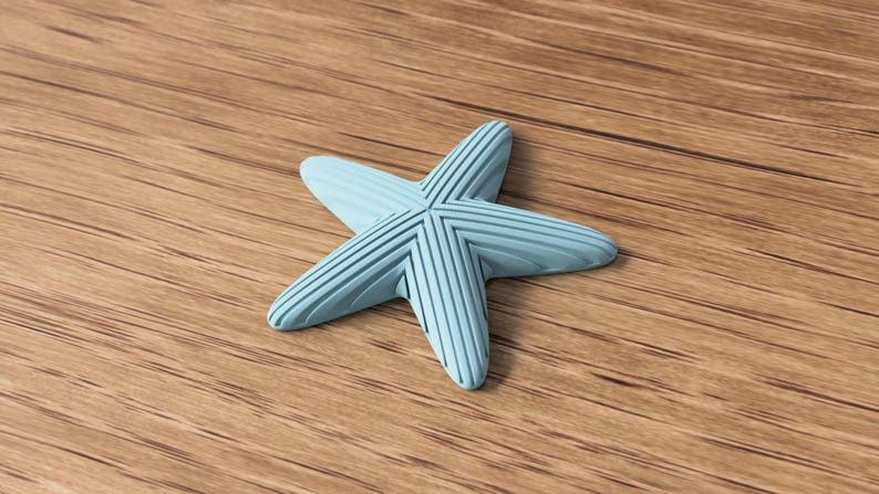May include: A light blue starfish-shaped decorative object with a textured surface. The five-pointed star is lying on a wooden surface. The starfish has a ribbed design on each point.