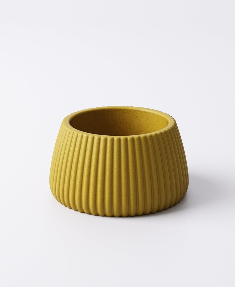 May include: Mustard yellow ceramic planter with vertical ribbed texture. The small, round planter has a wide opening and a slightly tapered shape. The exterior is a solid, matte color, and the interior is the same color. The planter is suitable for small plants.