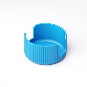 May include: A bright blue, semi-circular container with a ridged exterior and a smooth interior. The container has a curved back and two small, vertical extensions on either side. The object is set against a white background.