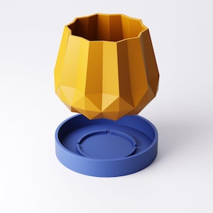 May include: A geometric, yellow planter with a faceted design, sitting above a blue, circular base. The planter has a wide, scalloped rim. The design is modern and minimalist, suitable for home decor.