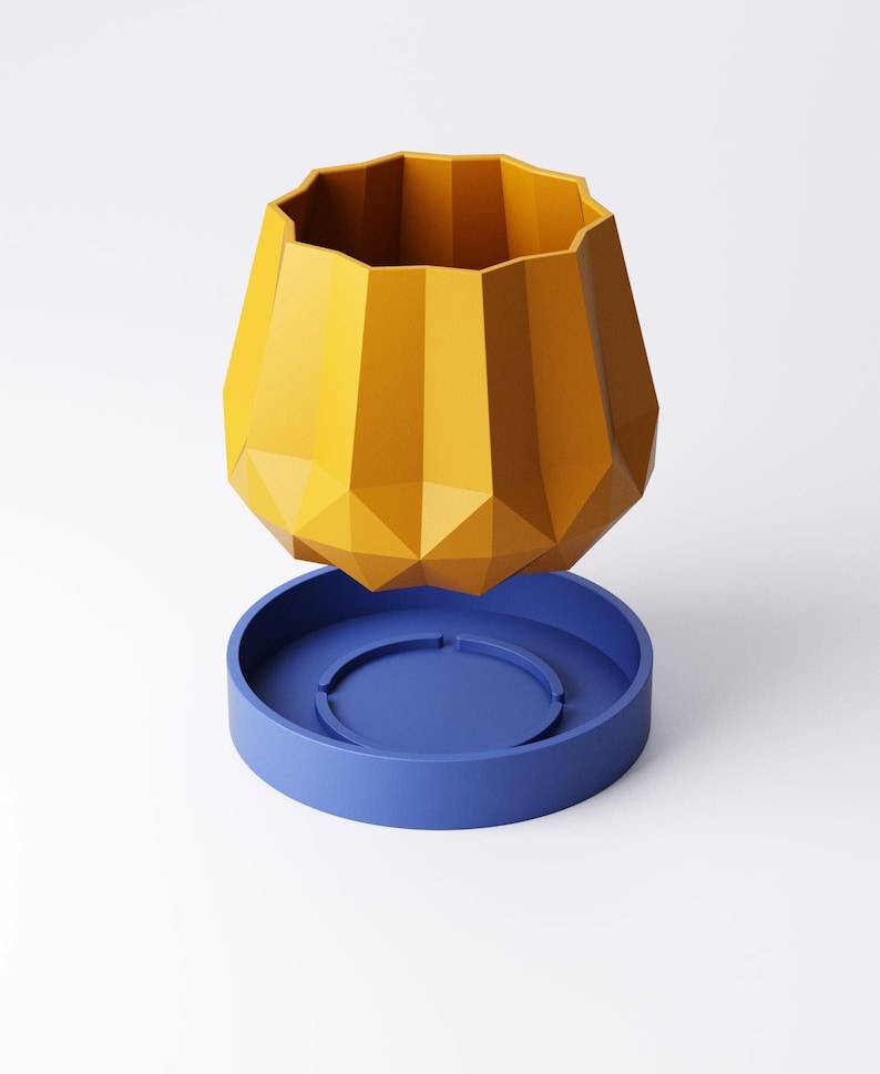 May include: A geometric, yellow planter with a faceted design, sitting above a blue, circular base. The planter has a wide, scalloped rim. The design is modern and minimalist, suitable for home decor.