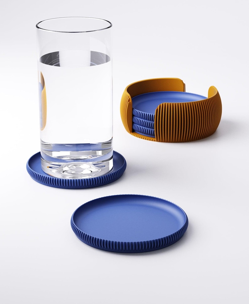 May include: A set of blue and orange coasters. The coasters are round with a ribbed edge. A glass of water sits on one coaster. The set includes a holder with a stack of coasters.