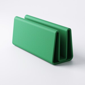 May include: A vibrant green, U-shaped desk organizer with a ribbed texture. The organizer is made of a solid material and has a modern, minimalist design. The item is designed to hold papers, files, or other office supplies.