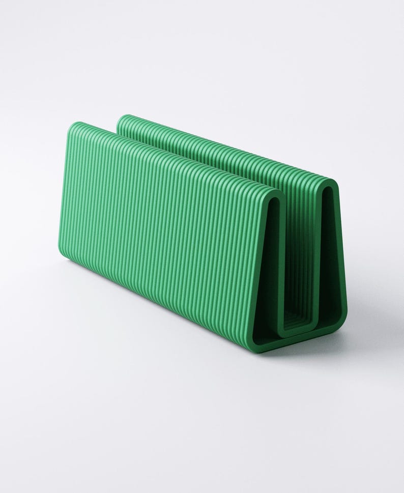 May include: A vibrant green, U-shaped desk organizer with a ribbed texture. The organizer is made of a solid material and has a modern, minimalist design. The item is designed to hold papers, files, or other office supplies.