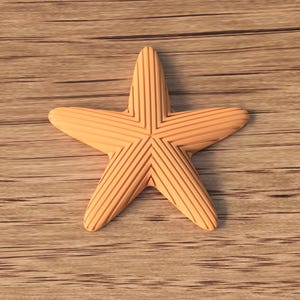 May include: A light orange starfish with etched lines, resting on a wooden surface. The starfish has five points and a detailed, textured design. The background is a light brown wood grain.