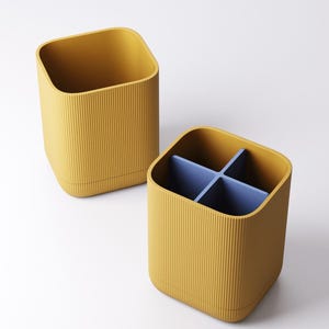 May include: Two mustard yellow storage containers with a ribbed texture. One container is empty, and the other has a blue divider creating four compartments. The containers have a square shape with rounded corners.