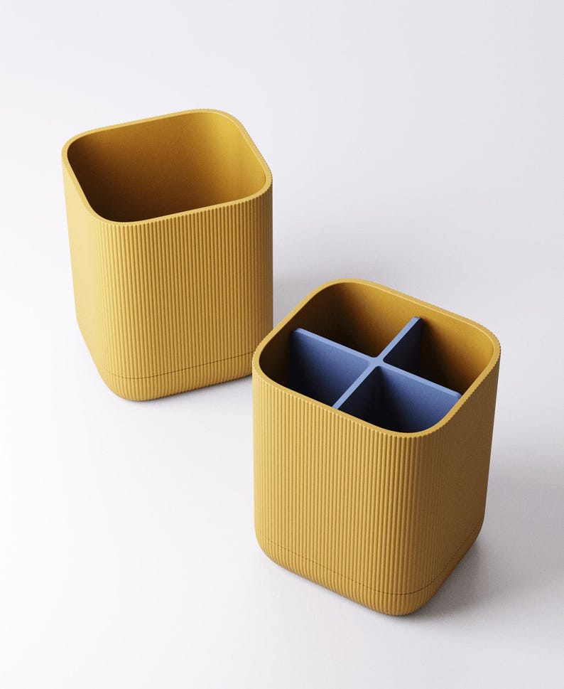 May include: Two mustard yellow storage containers with a ribbed texture. One container is empty, and the other has a blue divider creating four compartments. The containers have a square shape with rounded corners.