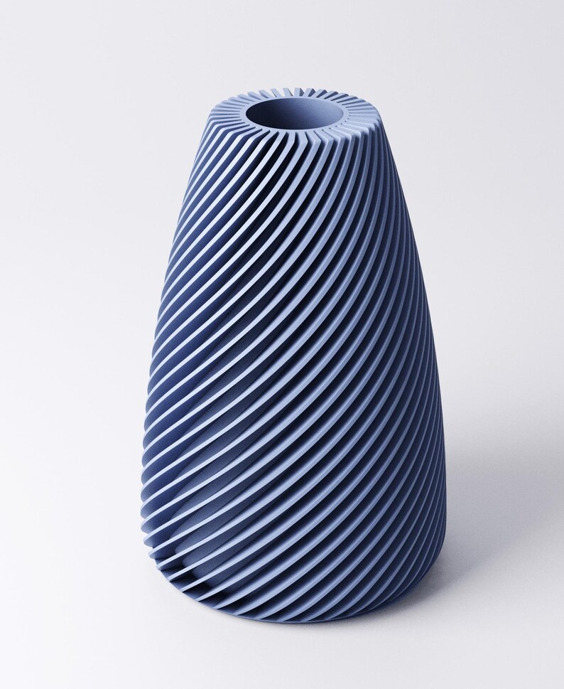 K&ouml;nnte beinhalten: Eine blaue Vase mit einem Spiraldesign. Die Vase hat einen breiten Boden, der sich zu einer schmaleren Oberseite mit einer kreisf&ouml;rmigen &Ouml;ffnung verj&uuml;ngt. Die Au&szlig;enseite weist eine Reihe paralleler, gebogener Linien auf, die eine strukturierte Oberfl&auml;che erzeugen. Die Vase besteht aus einem festen Material.