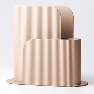 May include: A contemporary, beige-toned decorative piece with a ribbed surface. The design includes a tall, curved structure with a rounded top, and a smaller, cylindrical base. The object is set against a plain white backdrop.