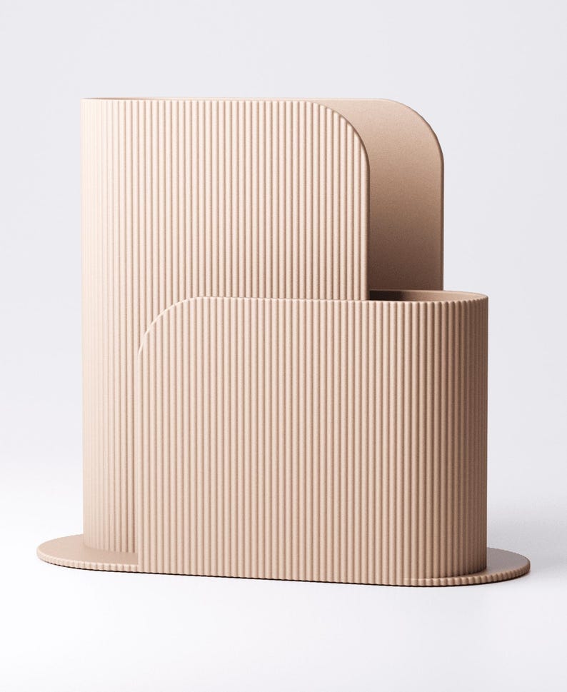 May include: A contemporary, beige-toned decorative piece with a ribbed surface. The design includes a tall, curved structure with a rounded top, and a smaller, cylindrical base. The object is set against a plain white backdrop.