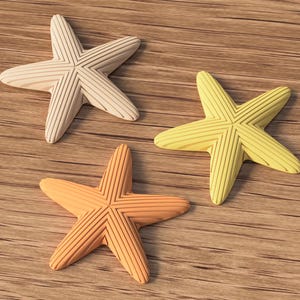 May include: Three starfish in shades of cream, yellow, and orange rest on a wooden surface. Each starfish has a textured, ridged design. The starfish are arranged in a triangular pattern.
