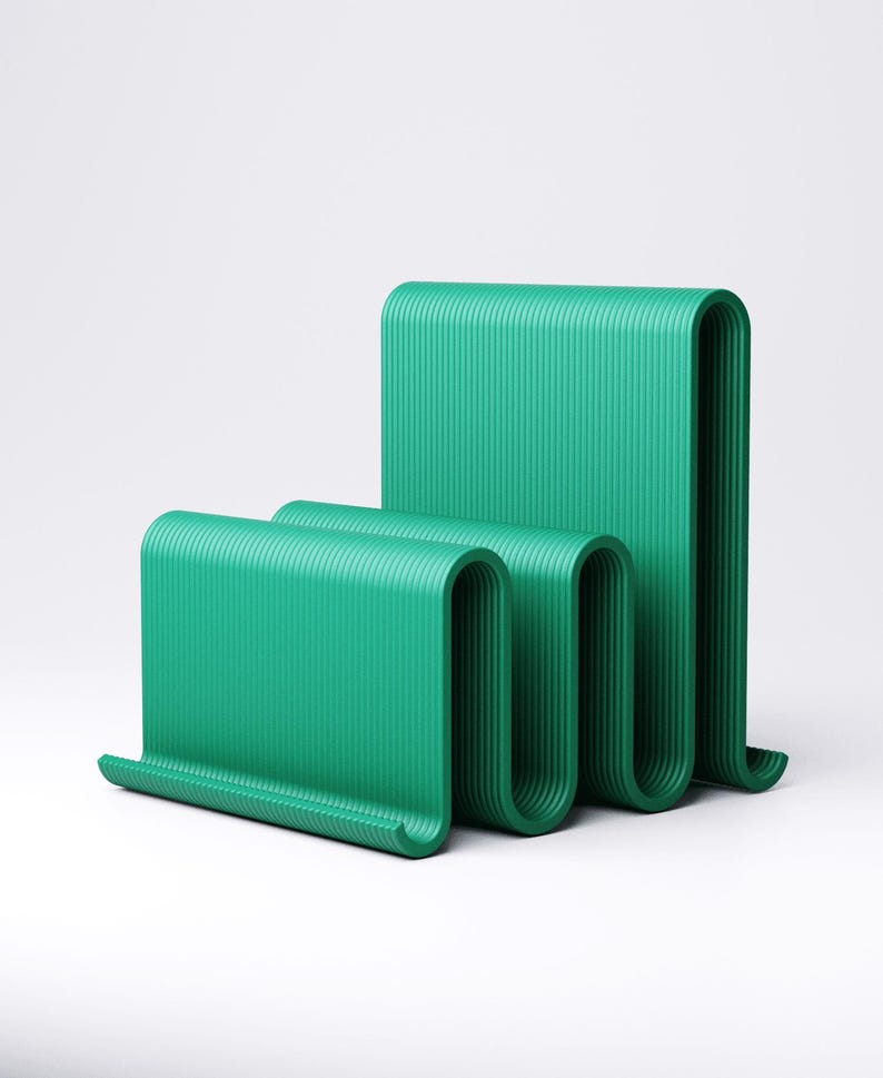 May include: Three abstract, green, wave-shaped sculptures. The sculptures have a ribbed texture and are arranged in a staggered formation. The color is a vibrant, solid green, and the background is plain white.