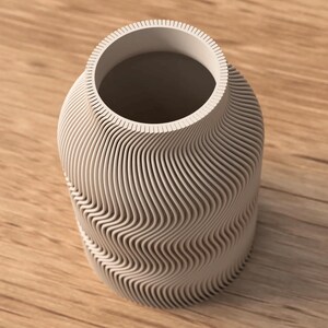 May include: A light gray vase with a unique, wave-like design. The vase has a cylindrical shape with a wide opening and a textured surface. The design is made up of horizontal, curved lines that create a flowing pattern.