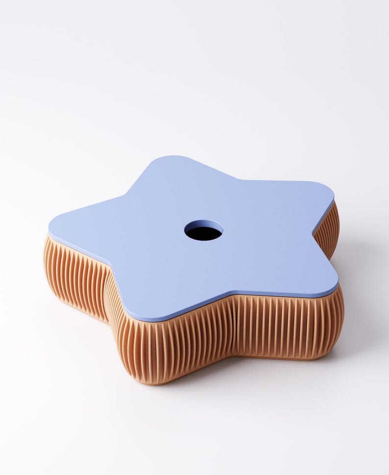 May include: A star-shaped, light blue table with a hole in the center. The table's sides are a light brown, ribbed design. The table is a unique piece of furniture.