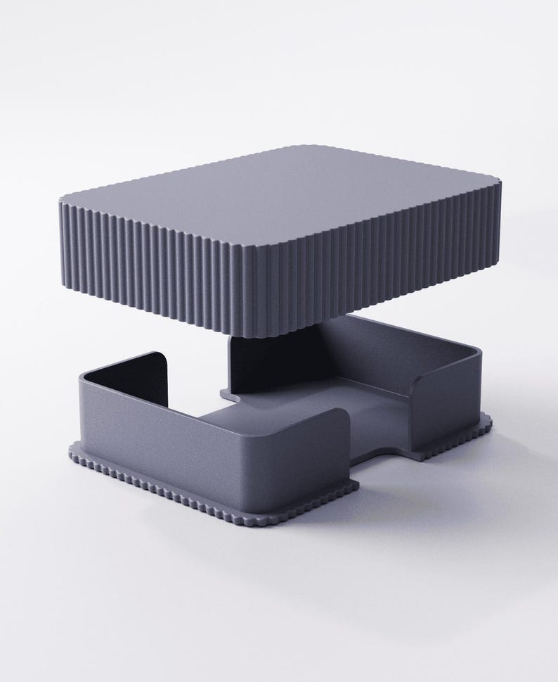 May include: A modern, two-piece, gray desk organizer. The top section is a rectangular tray with vertical ridged sides. The bottom section has a tray with curved sides and a scalloped edge. The organizer is made of a solid, matte material.