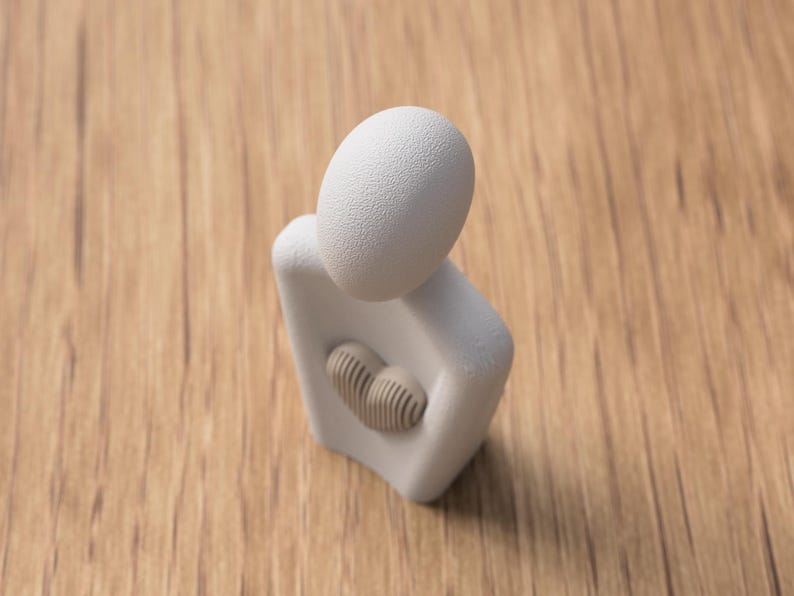 Puede incluir: Una escultura abstracta blanca de una persona abrazando un coraz&oacute;n. La escultura tiene una cabeza texturizada en forma de huevo y un recorte en forma de coraz&oacute;n lleno de un dise&ntilde;o beige y acanalado. La escultura est&aacute; sobre una superficie de madera.