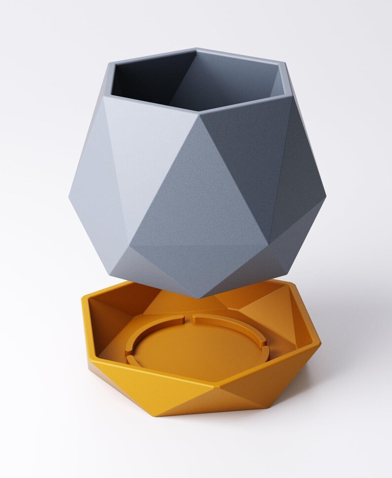 May include: A geometric, two-piece planter set. The upper planter is a faceted, gray polygon shape. The lower piece is a matching faceted polygon in a mustard yellow color, designed to catch water. The planter is designed to hold small plants.