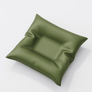 May include: Olive green square cushion with a slightly textured surface. The cushion has a rectangular indentation in the center. The pillow is angled, showing its shape and the way it catches the light.