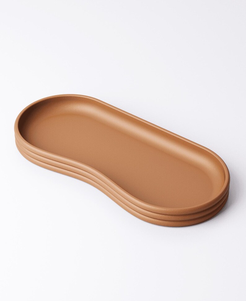 May include: A brown, oval-shaped serving tray with a raised edge and a ridged base. The tray is made of a solid material and has a smooth surface. The design is minimalist and modern, suitable for serving food or displaying items.