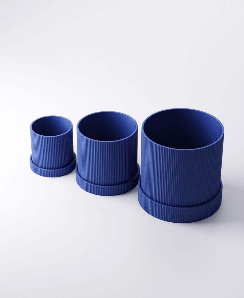 May include: Three blue cylindrical planters of varying sizes, each with a matching base. The planters have a ribbed texture on the exterior. The smallest planter is approximately 4 inches in diameter, while the largest is about 8 inches.