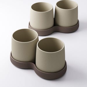 May include: Four beige, ribbed ceramic planters with a brown, wavy base. The planters are cylindrical with a textured, vertical stripe design. The bases are a darker brown and connect two planters together. The planters are empty.