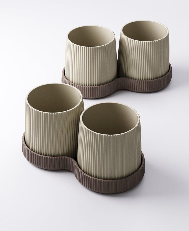 May include: Four beige, ribbed ceramic planters with a brown, wavy base. The planters are cylindrical with a textured, vertical stripe design. The bases are a darker brown and connect two planters together. The planters are empty.