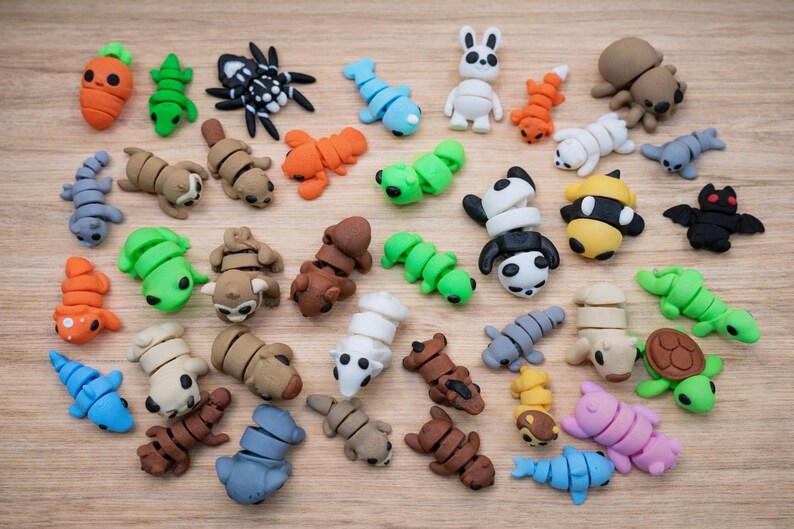Op de afbeelding: Een verzameling kleurrijke, miniatuur gummen in de vorm van dieren en voedsel. De gummen omvatten een wortel, een spin, een konijn, een panda en een schildpad. Ze zijn gerangschikt op een lichtbruin houten oppervlak.