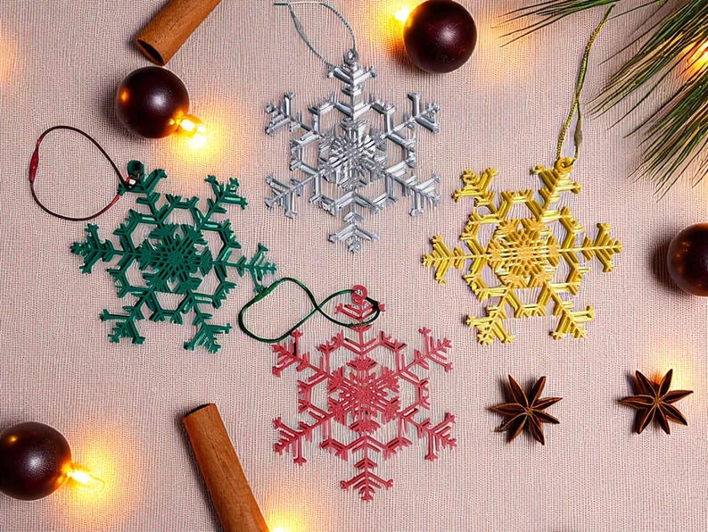 May include: A collection of snowflake ornaments in silver, green, gold, and red. The ornaments are arranged with cinnamon sticks, star anise, and decorative lights, creating a festive holiday scene.